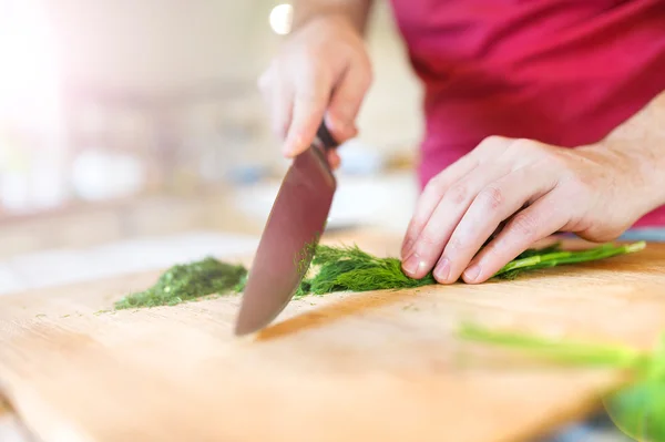 Man in the kitchen cutting dill — Stock Photo, Image