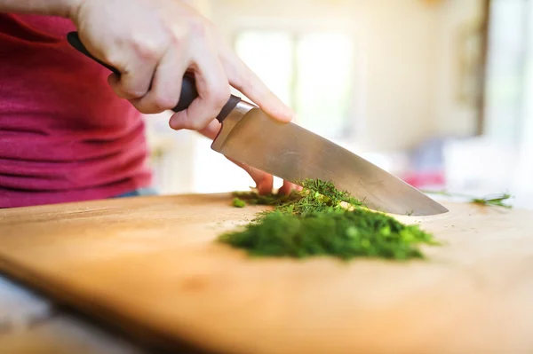 Hombre en la cocina cortando eneldo — Foto de Stock