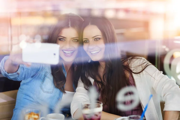 Two beautiful women taking selfie in cafe — Stock Photo, Image