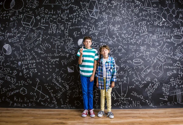 Lindo niño y niña delante de una gran pizarra . —  Fotos de Stock