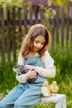 Bahçede yavru hayvanlarla oynayan gülümseyen bir çocuk. Çiftlikte hayat.