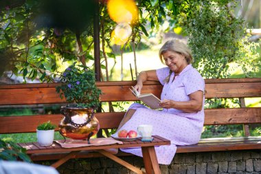 Yaşlı bir kadın için Selfacare anı, bahçedeki sessiz okuma zamanı. Hint Yazı.