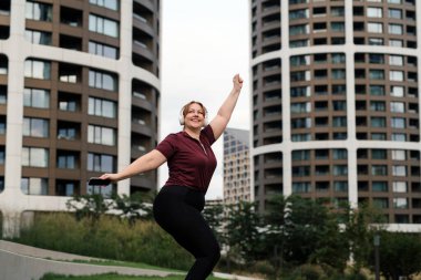 Vücut pozitifliği olan kadın antrenmandan önce ısınıyor, dışarıda egzersiz yapıyor..