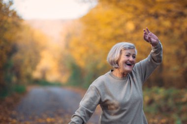 Sonbahar ormanlarında gezen yaşlı bir kadın..