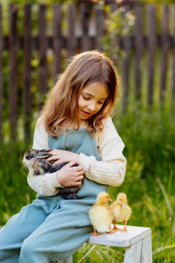 Bahçede yavru hayvanlarla oynayan gülümseyen bir çocuk. Çiftlikte hayat.