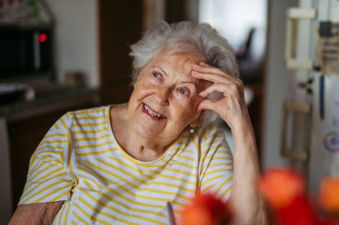 Mutfakta ağlayan, yüzünü kapatan endişeli yaşlı kadının portresi..