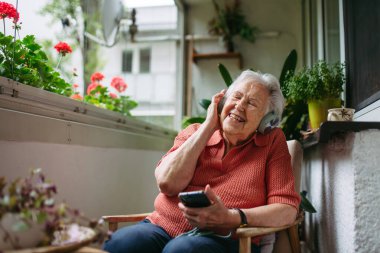 Akıllı telefondan podcast dinleyen son sınıf öğrencisinin portresi, kafasında kulaklık..