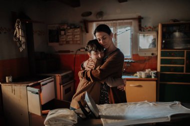 Bekar bir anne zor zamanlarda çocuğuna sarılıyor. Yoksulluk kavramı.