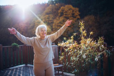 Kıdemli kadın sıcak sonbahar güneşinin tadını çıkarıyor. Sonbahar ve son sınıflar.