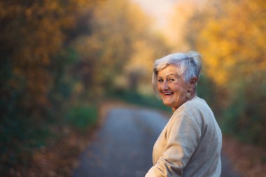 Sonbahar ormanlarında gezen yaşlı bir kadın..