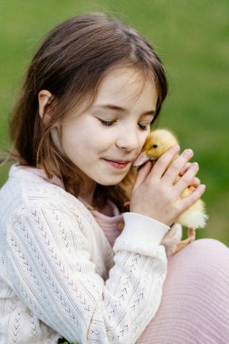 Bahçedeki genç kız sarı yavru ördekle oynuyor..