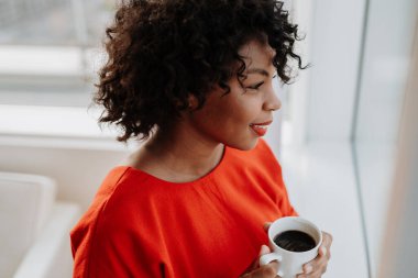 Bir close-up pencere holding kahve Kupası tarafından ayakta, aşağı bakıyor bir kadın. Kopya alanı.