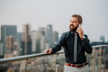 İş adamı modern ofisin terasında telefon görüşmesi yapıyor. Londra çatı manzaralı panorama.