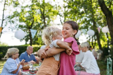 Kız kardeşi küçük kardeşiyle bir aile bahçe partisinde oynuyor..
