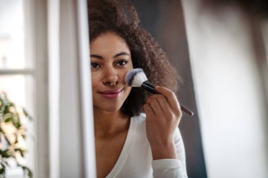 Aynanın önünde makyaj yapan genç bir kadının yakın çekimi..