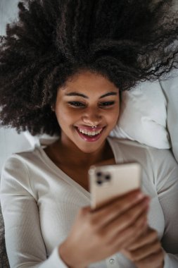 Akıllı telefon kullanan, yatakta yatan güzel bir kadının portresi..