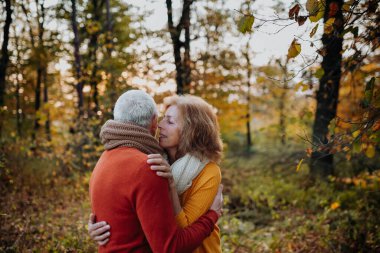 Son sınıf çifti arasındaki romantik an, sonbahar doğasının ortasında duruyor..