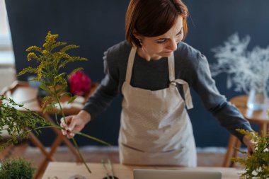 Küçük çiçekçisinde çalışan genç bir bayan çiçekçi..
