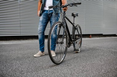 Kasklı ve sırt çantalı bir adam işe bisikletle gidiyor.