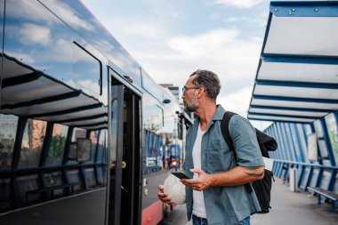 Olgun bir adam otobüse biniyor. Toplu taşıma kavramı. Kentsel banliyö.