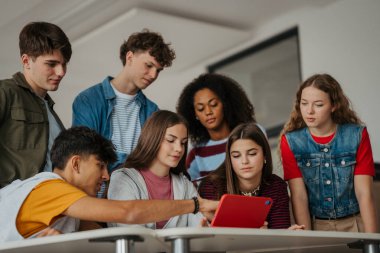 Genç öğrenciler modern sınıfta dijital tabletle birlikte öğreniyorlar..