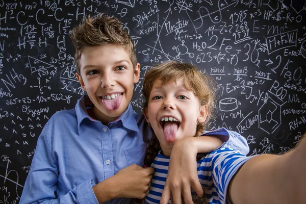 Söt liten pojke och flicka framför en stor svart tavla. — Stockfoto