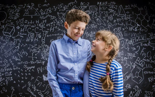 Lindo niño y niña delante de una gran pizarra . — Foto de Stock