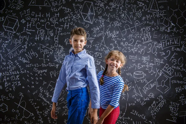 かわいい男の子と女の子大きな黒板の前に. — ストック写真