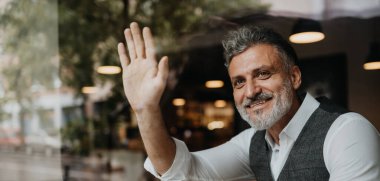 Kafede oturan bir adamın portresi, pencerenin arkasında birini selamlıyor..