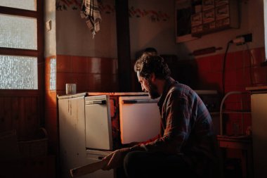 Yaşlı iç mekanında odun sobasının yanında oturan yoksul adam. Yoksulluk kavramı.