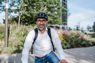 İşe bisikletle, işe giderken, sırt çantası ve kaskla..