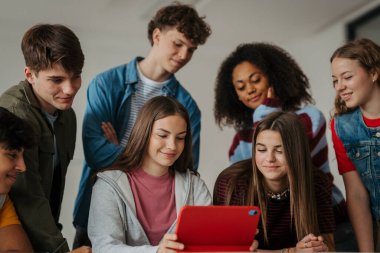 Genç öğrenciler modern sınıfta dijital tabletle birlikte öğreniyorlar..