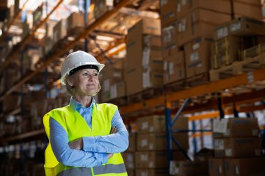 Bir kadın kıdemli Yöneticisi veya Yöneticisi ile beyaz kask ayakta bir depoda geçti silah portresi. Kopya alanı.