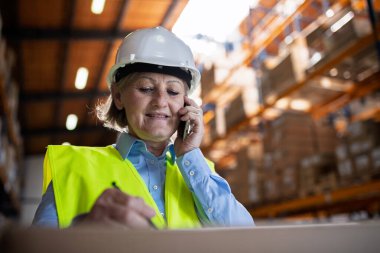 Akıllı telefonlu bir bayan depo müdürü ya da amiri bir telefon görüşmesi yapıyor. Boşluğu kopyala.