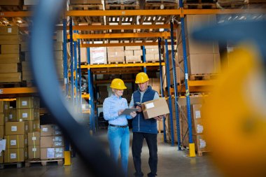 Kadın kıdemli Yöneticisi ve barkod tarayıcı birlikte çalışma bir depo ile bir adam işçi.