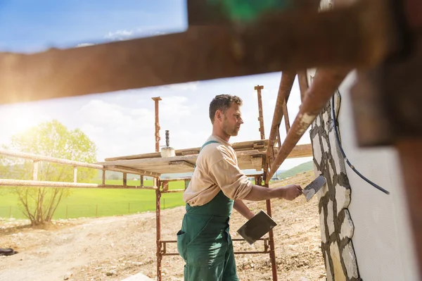 Mann legt Natursteine an eine Wand — Stockfoto