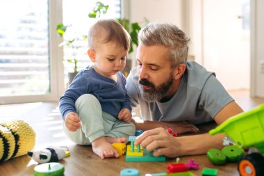 Baba yerde oğluyla oyuncak oynuyor..