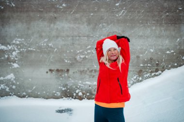 Soğuk karlı havada koşan aktif yaşlı bir kadın. Kış egzersizi.