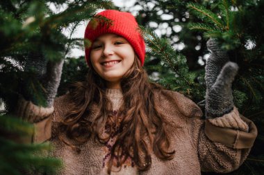 El yapımı bir Noel çelengi tutan kız, ona bakıyor..