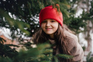 El yapımı bir Noel çelengi tutan kız, ona bakıyor..