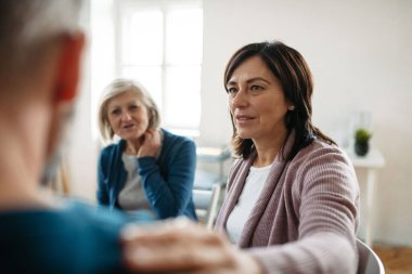 İnsanlar bir çemberin içinde oturup terapi seansı sırasında acı tecrübelerini paylaşıyorlar. Empatik omuz dokunuşu.