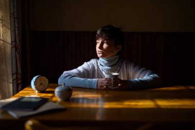 Üzgün yetim kız masada tek başına oturuyor..