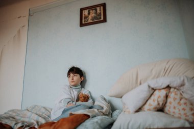 Üzgün yetim kız yatak odasında tek başına oturuyor..