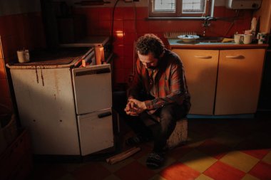 Yaşlı iç mekanında odun sobasının yanında oturan yoksul adam. Yoksulluk kavramı.