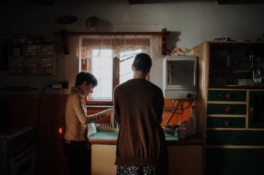 Eski bir kırsal mutfakta annesinin bulaşık yıkamasına yardım eden bir kız. Yoksulluk kavramı..