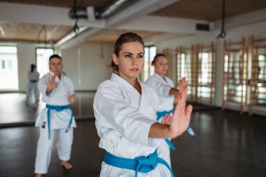 Odaklanmış kadın karate dövüşçüleri sanat stüdyosunda yumruk tekniği uyguluyor..