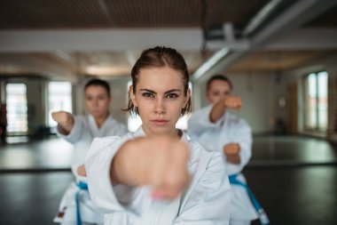 Odaklanmış kadın karate dövüşçüleri sanat stüdyosunda yumruk tekniği uyguluyor..
