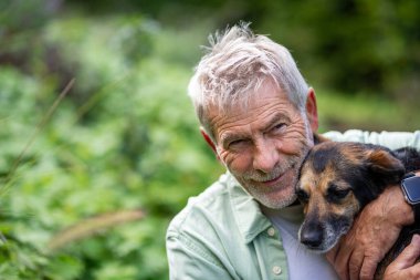 Huzur içinde yürürken evcil köpekle bağ kuran yaşlı bir adam.