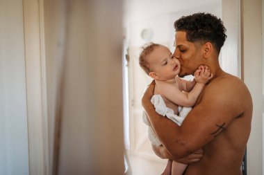 Babasının kucağında havluya sarılı küçük bir oğlu var..