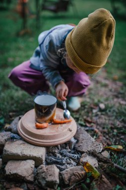 Ev yapımı kamp ateşi ızgarasında sebze kızartan küçük kız, ateş çukuru.